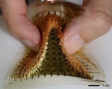 白い風船の上に、多点の圧力センサーのシートを密着させ、指で大きく変形させた。圧力センサーの素材は透明だが、多点化したセンサーから圧力データを読み出すための回路で使われている電極や配線は透明ではなく、金色に見えている