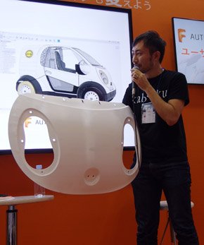ボンネットの3Dプリントパーツを手にプロジェクトの概要を説明する横井さん